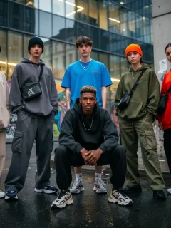 Diverse individuals modeling contemporary gender-neutral streetwear in an urban environment.